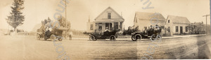 Image of Trio of touring cars pausing on the road in front of houses